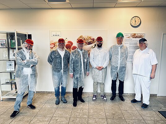 Gruppenbild Teilnehmende nach der Werksführung mit Mantel und Helm